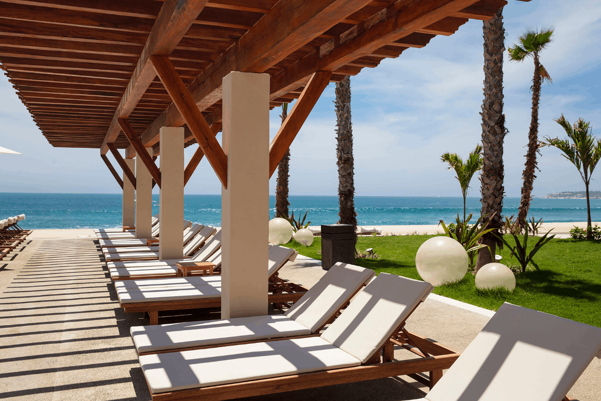 Oceanfront lounge chairs at Krystal Grand Los Cabos with shaded areas and Sea of Cortes views.