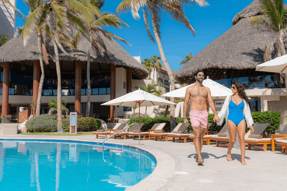 Couple walking by the pool at Krystal Grand Los Cabos during an All Inclusive vacation.